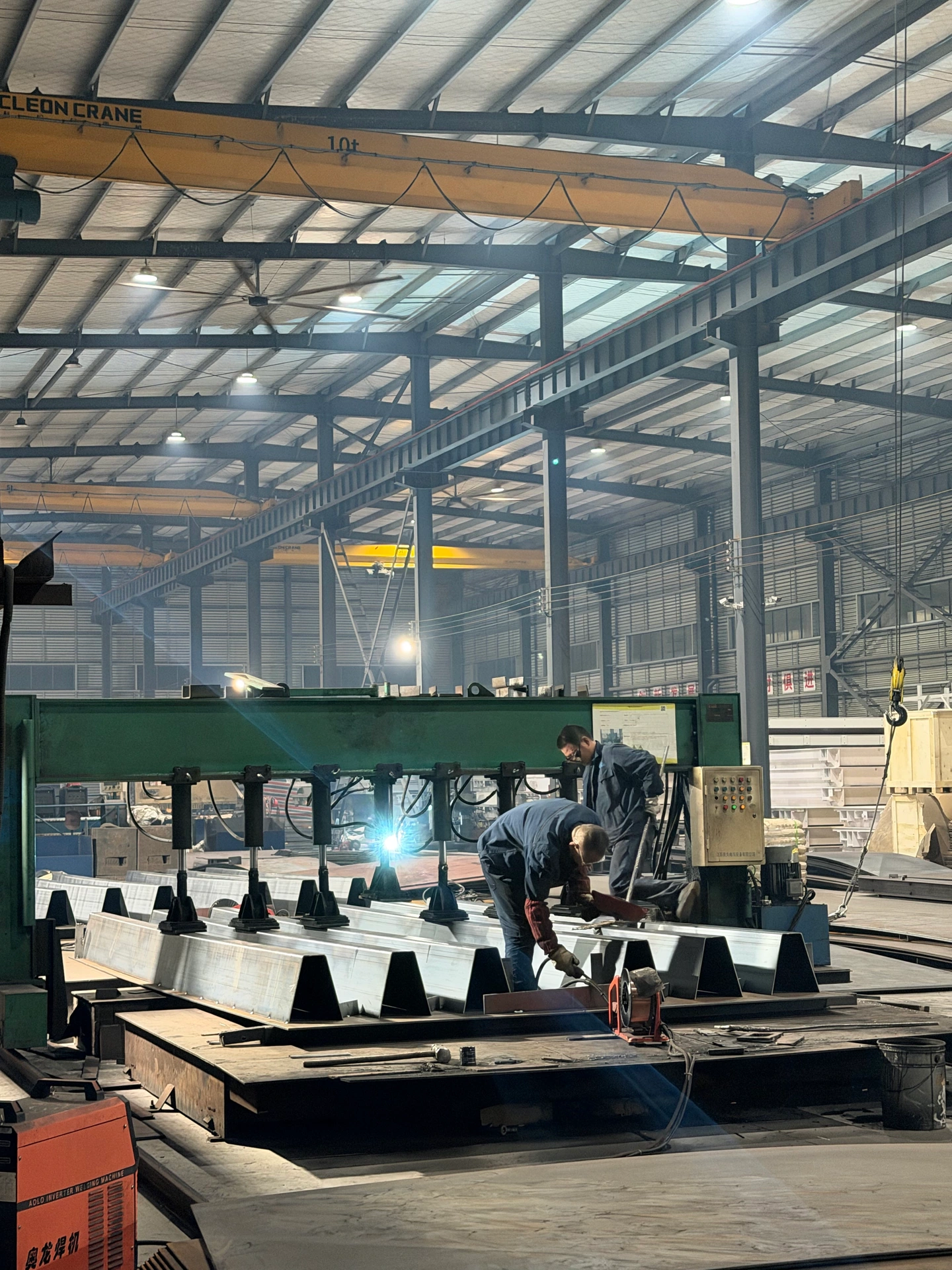 HENER workshop staff working on a steel platform frame beneath an overhead crane