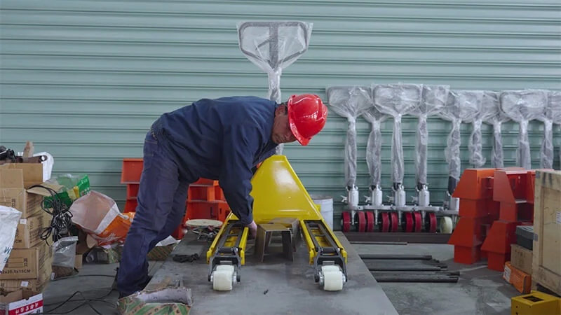 HENER worker assembling a finished yellow pallet jack